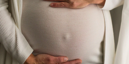 A pregnant woman cradling her tummy A pregnant woman cradling her tummy